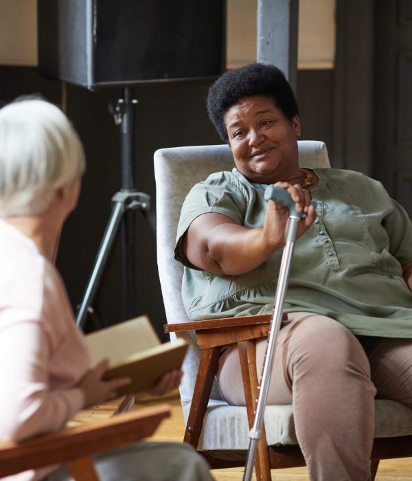 Portrait of senior African-American woman talking to friends while enjoying retirement in nursing home